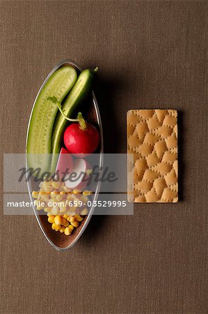 Raw vegetables in bowl with crispbread