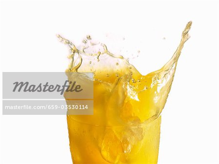 Orange juice splashing out of a glass