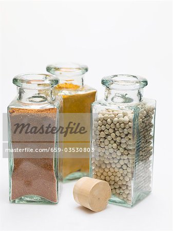 Nutmeg, turmeric, white peppercorns in spice bottles