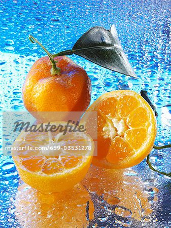 Mandarin oranges on reflective surface with drops of water