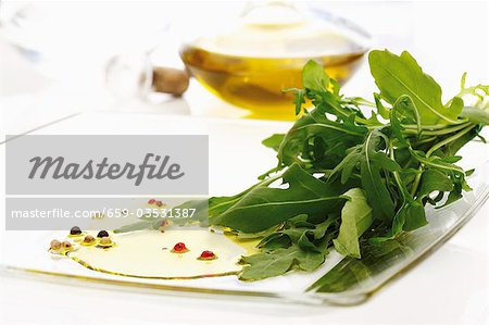 Fresh rocket on chopping board, olive oil