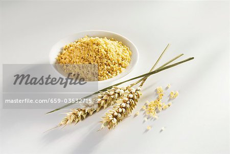 Bulgur in small dish, ears of wheat ears beside it Bulgur in small dish, ears of wheat ears beside it