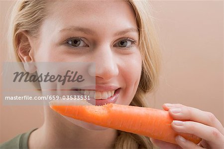 Woman holding a carrot with a bite taken