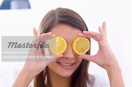 Girl holding lemon slices in front of her eyes