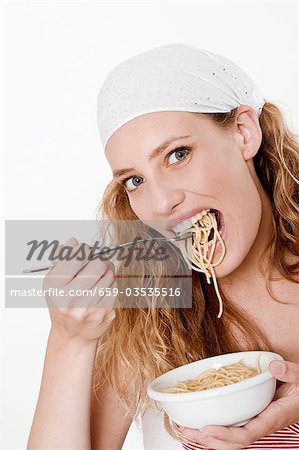 Young woman with headscarf eating spaghetti