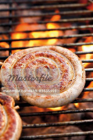 Coiled sausage on barbecue rack (close-up)