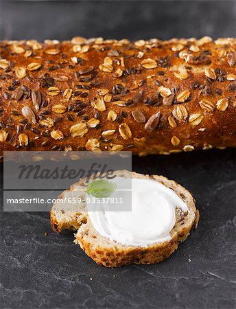 Multigrain baguette and baguette slice with cream cheese and basil leaf