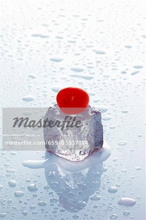Ice cube with cherry on wet surface