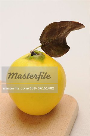 A quince with a leaf on a chopping board