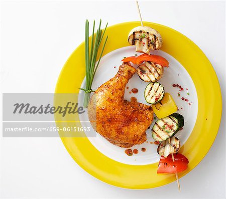 A chicken leg with a grilled vegetable kebab A chicken leg with a grilled vegetable kebab
