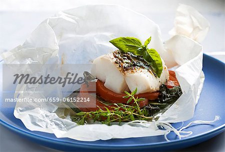 Fish fillet with tomatoes and courgette in baking paper