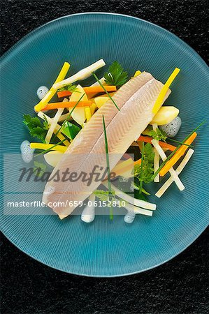 Poached trout fillet with root vegetables and herbs