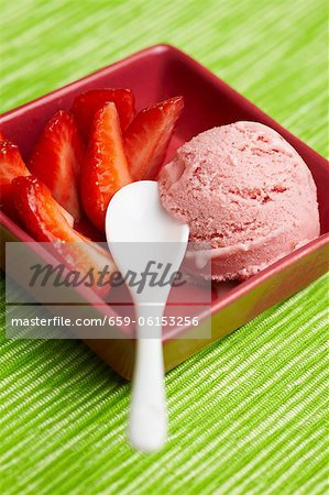 Strawberry ice cream with fresh strawberries in a bowl with a spoon