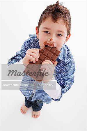 A little boy eating a bar of chocolate