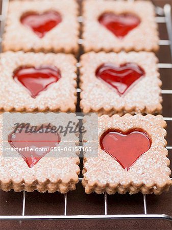 Jam biscuits with icing sugar on a wire rack