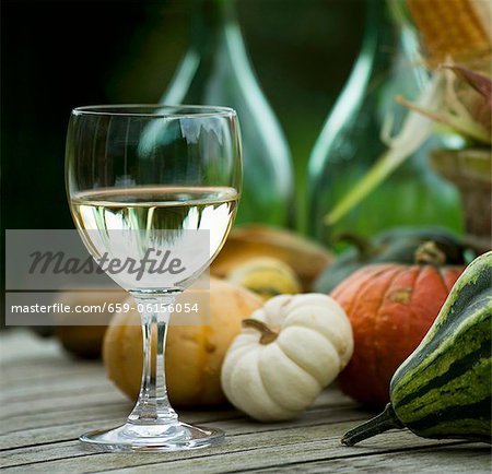 A glass of white wine and pumpkins on a wooden table