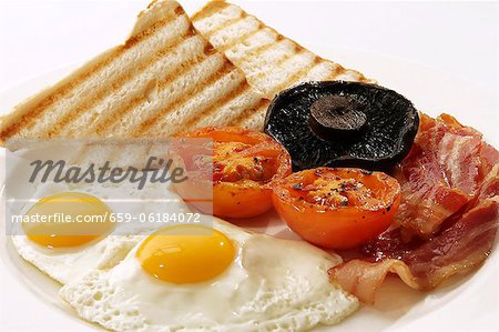 English breakfast with fried egg, bacon, tomatoes, mushrooms and toast