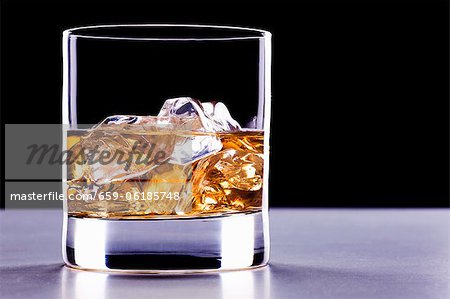 A glass of whisky with ice cubes