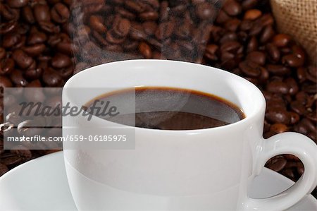 A cup of coffee against a backdrop of coffee beans