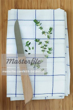 Thyme sprigs and leaves on a tea towel with a knife