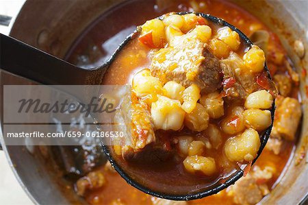 Red Posole; Mexican Hominy Stew; Made with Pork; In Ladle Above Pot Red Posole; Mexican Hominy Stew; Made with Pork; In Ladle Above Pot