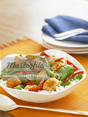 Chicken Stir Fry with Snow Peas and Red Peppers Over Rice in a Serving Bowl