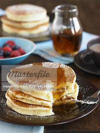 Stack of Buttermilk Pancakes with Syrup and Powdered Sugar; Bite Taken Out