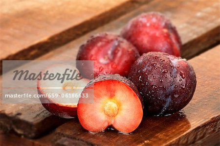 Plums, whole and halved, on wooden crate