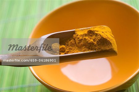 Turmeric powder on a wooden scoop