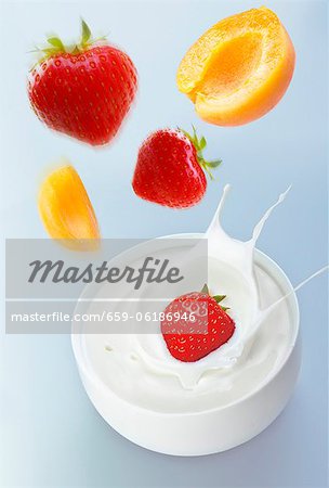 Apricots and strawberries falling into yogurt