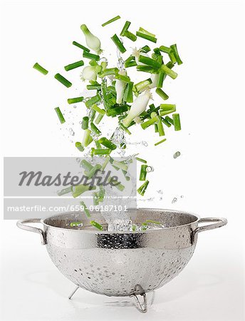 Spring onions and splash of water falling into a colander