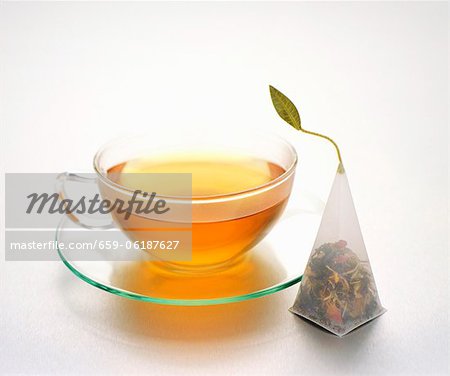 Tea in a glass tea cup next to a tea bag