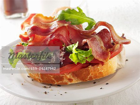 A slice of baguette topped with bacon, lettuce and tomato