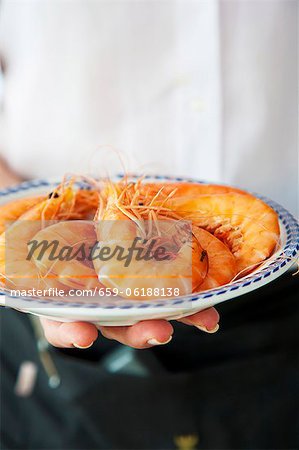 A waitress serving a plate of king prawns