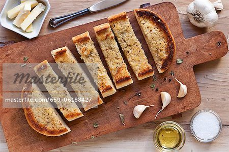 Garlic Bread Sliced on a Wooden Cutting Board; From Above; Ingredients for Garlic Bread