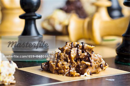 Nut brittle drizzled with chocolate on a chessboard