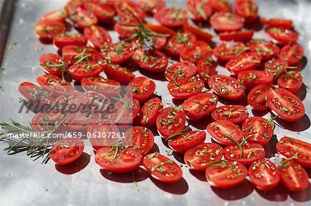 Tomatoes with rosemary on a baking tray to dry