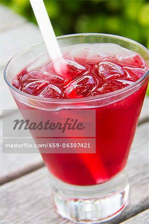 Absolute Vodka and Cranberry Juice Cocktail in a Glass with Ice and a Straw; Outdoors