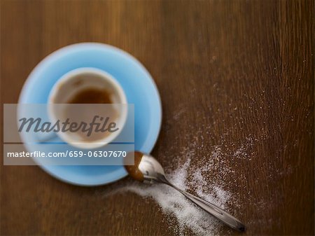 An almost-empty espresso cup and sugar sprinkled next to it