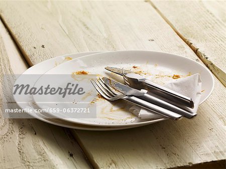 A dirty plate with cutlery and a paper napkin A dirty plate with cutlery and a paper napkin
