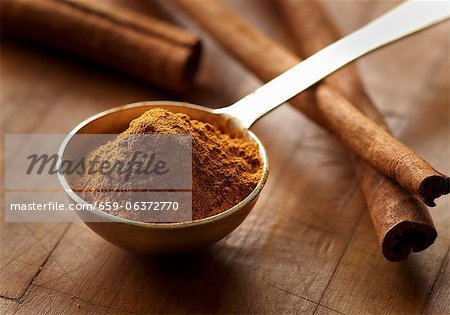 Ground Cinnamon in a Measuring Spoon; Cinnamon Sticks