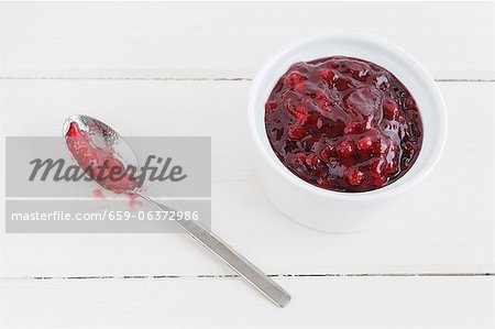 Stewed lingonberries in a bowl with a spoon