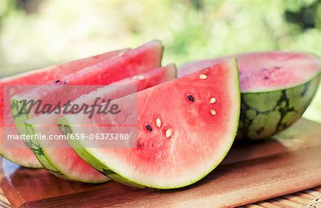 Watermelon Slices and Half a Watermelon on a Cutting Board; Outdoors