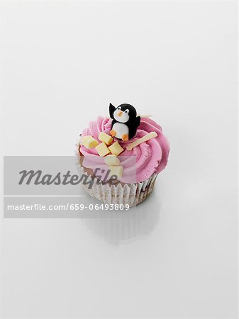 A cupcake decorated with strawberry cream and penguin