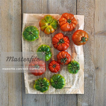 Red and green beefsteak tomatoes on a piece of newspaper