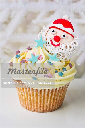 A vanilla cupcake decorated with a Father Christmas and sugar stars