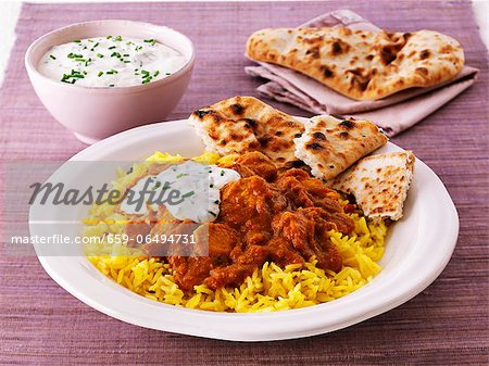 Chicken curry with rice, unleavened bread and a yoghurt dip