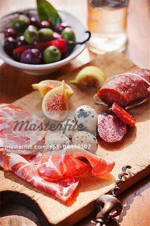 Cutting Board with Prosciutto, Quail Eggs, Figs and Salami; Bowl of Mixed Olives