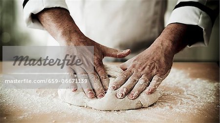 A chef kneading pizza dough