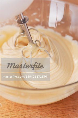 Cake batter being mixed with a mixer in a glass bowl Cake batter being mixed with a mixer in a glass bowl